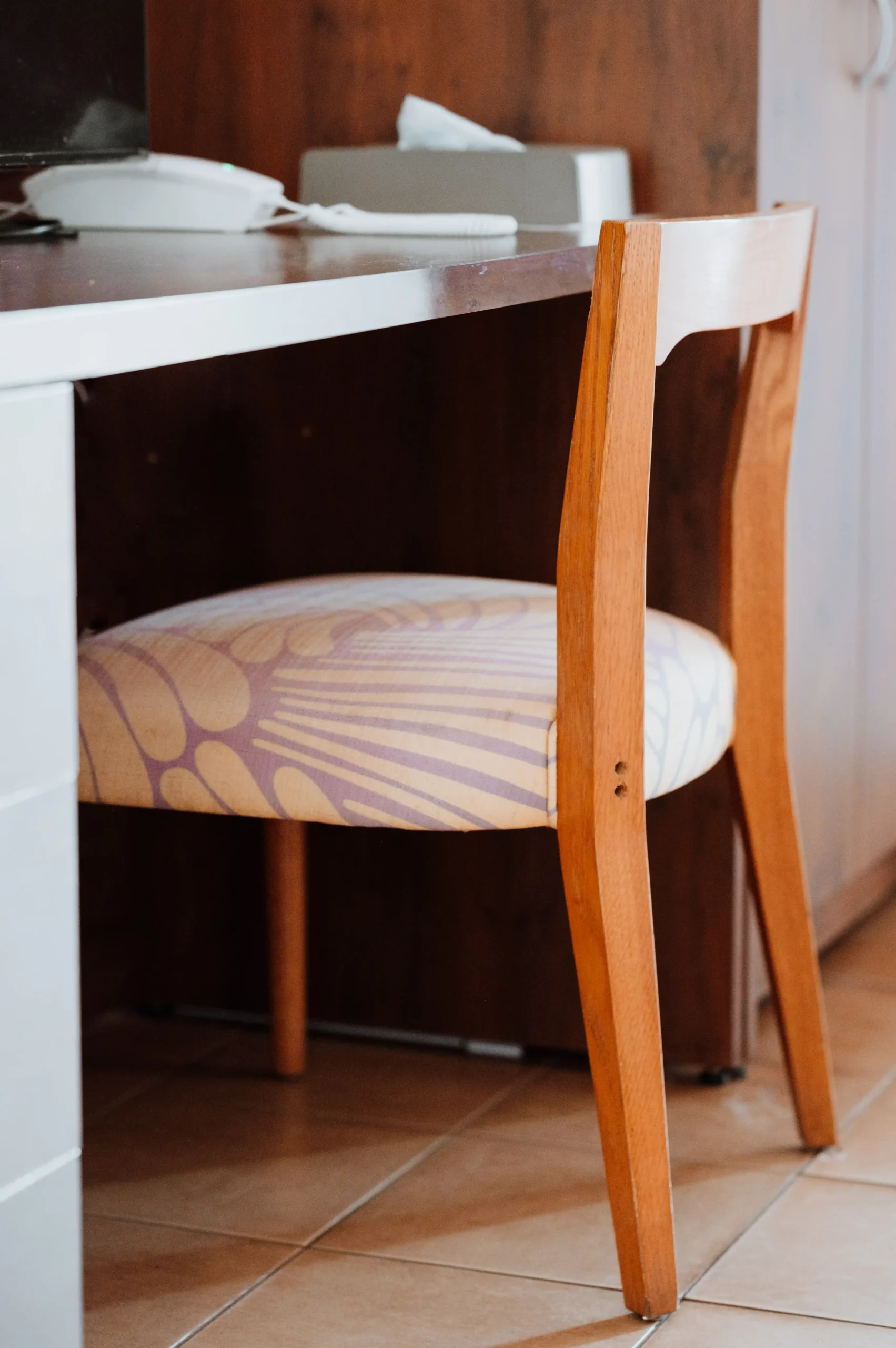 a close up of a stylish 60s style chair with tropical fabric at a desk