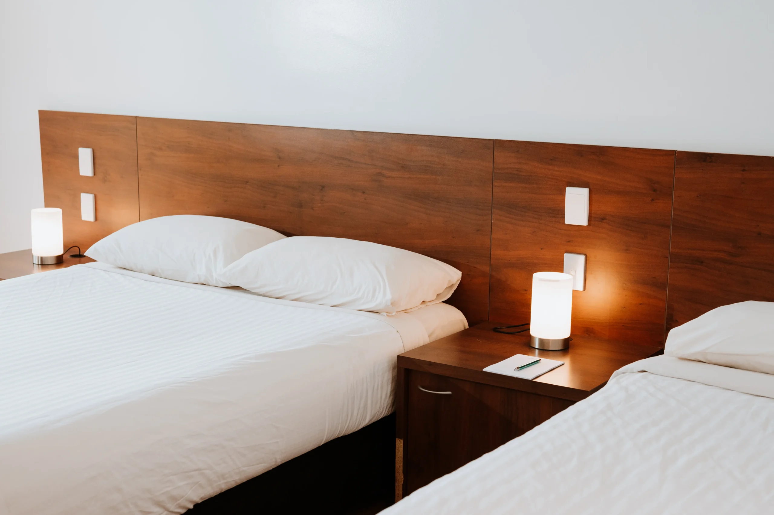 Photo of two beds in a deluxe room, showing a bedside table between the white sheeted beds