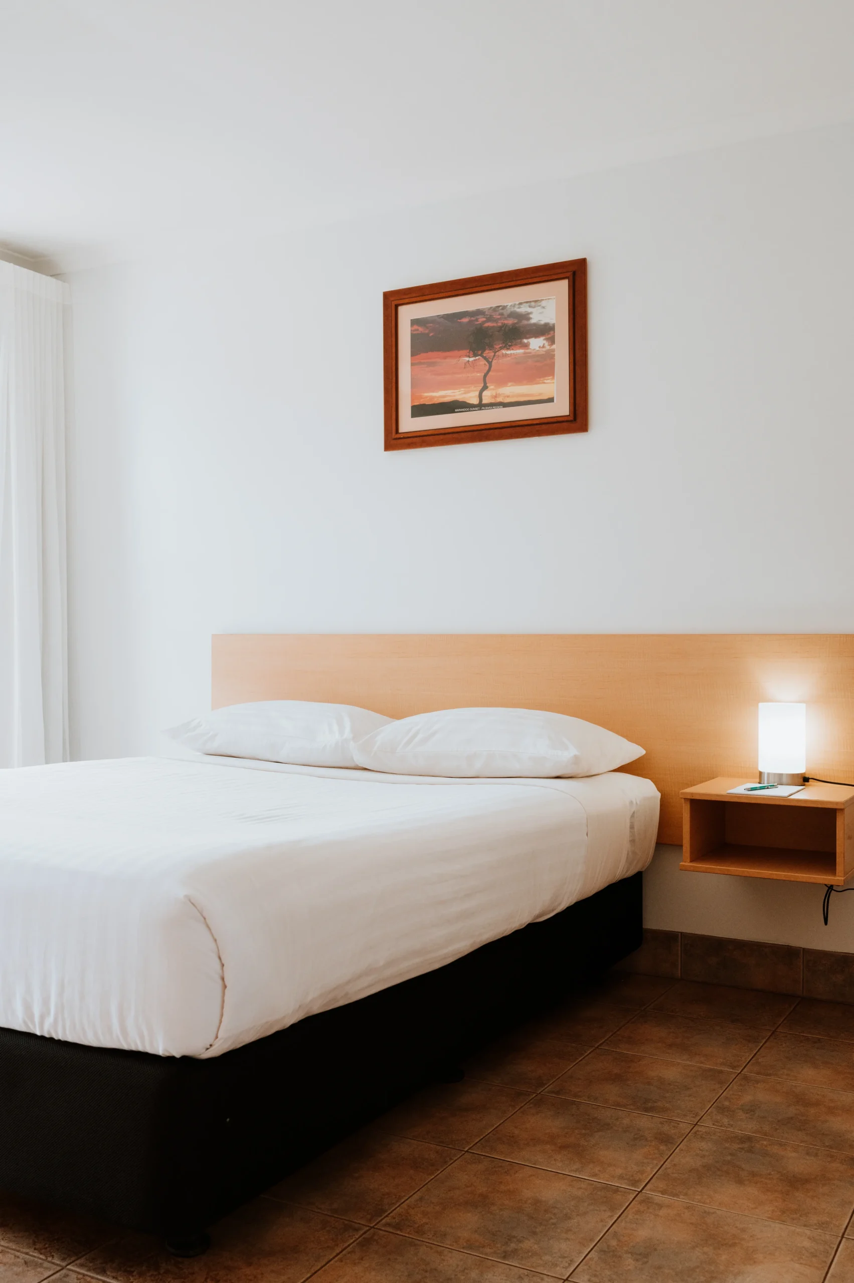 view of bed with white sheets in deluxe room with ocean view