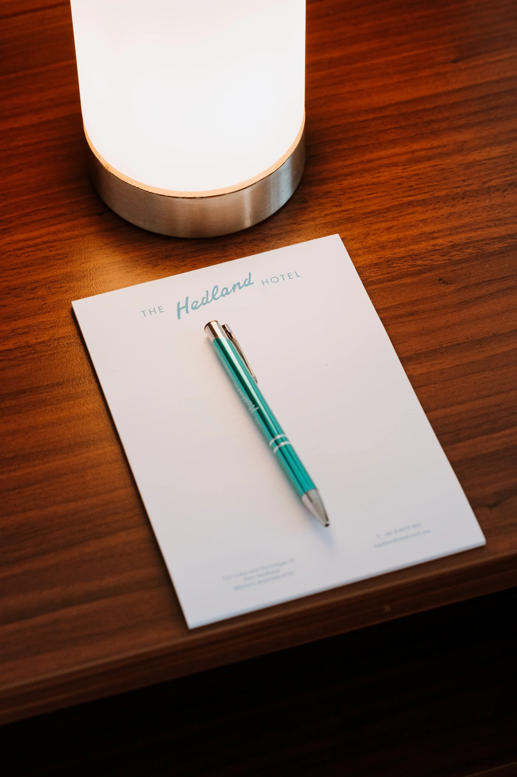 a close up of a pen and paper with The Hedland Hotel logo on the bedside table