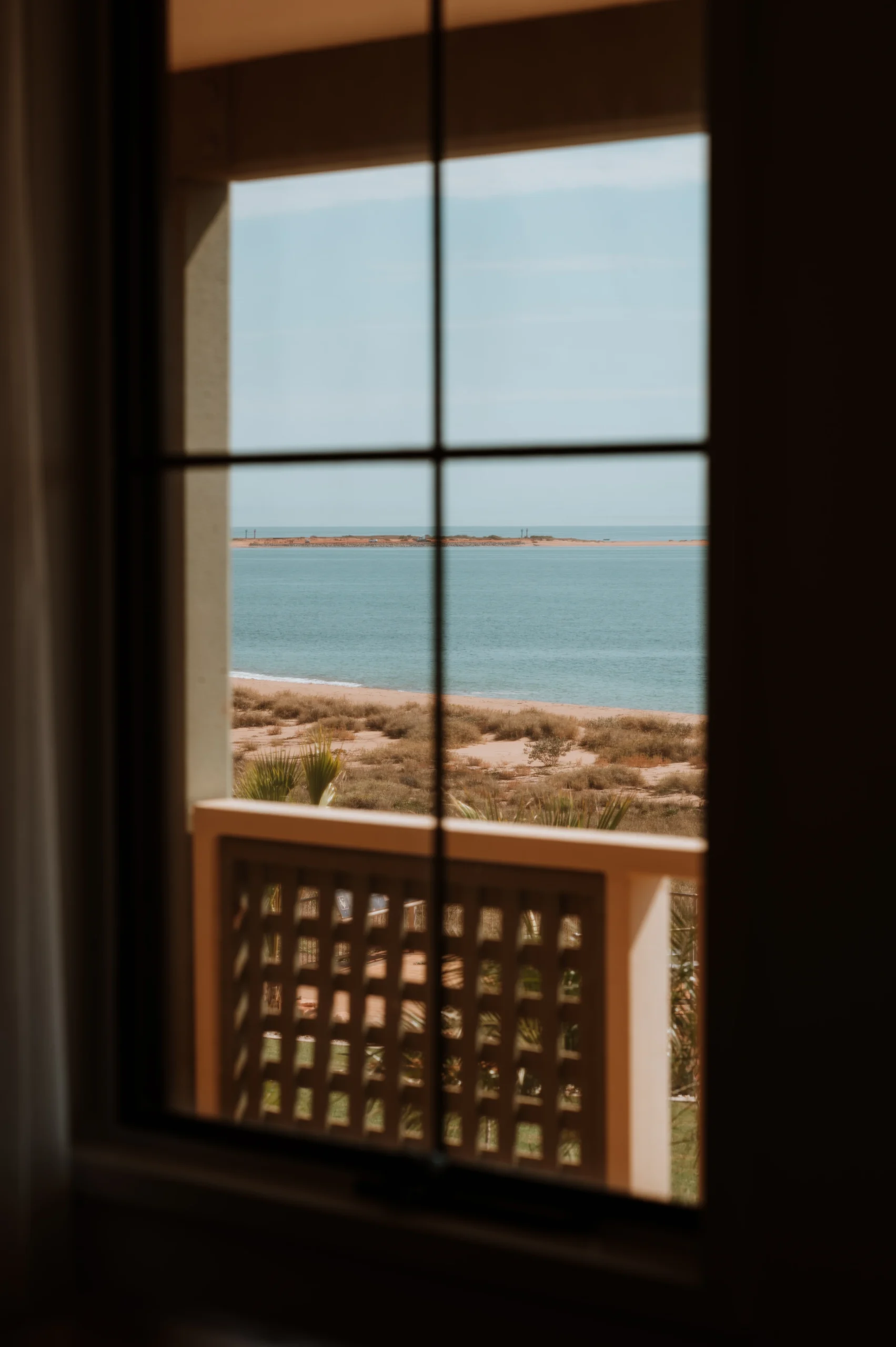 a view of the beach through a window in a deluxe room with ocean view