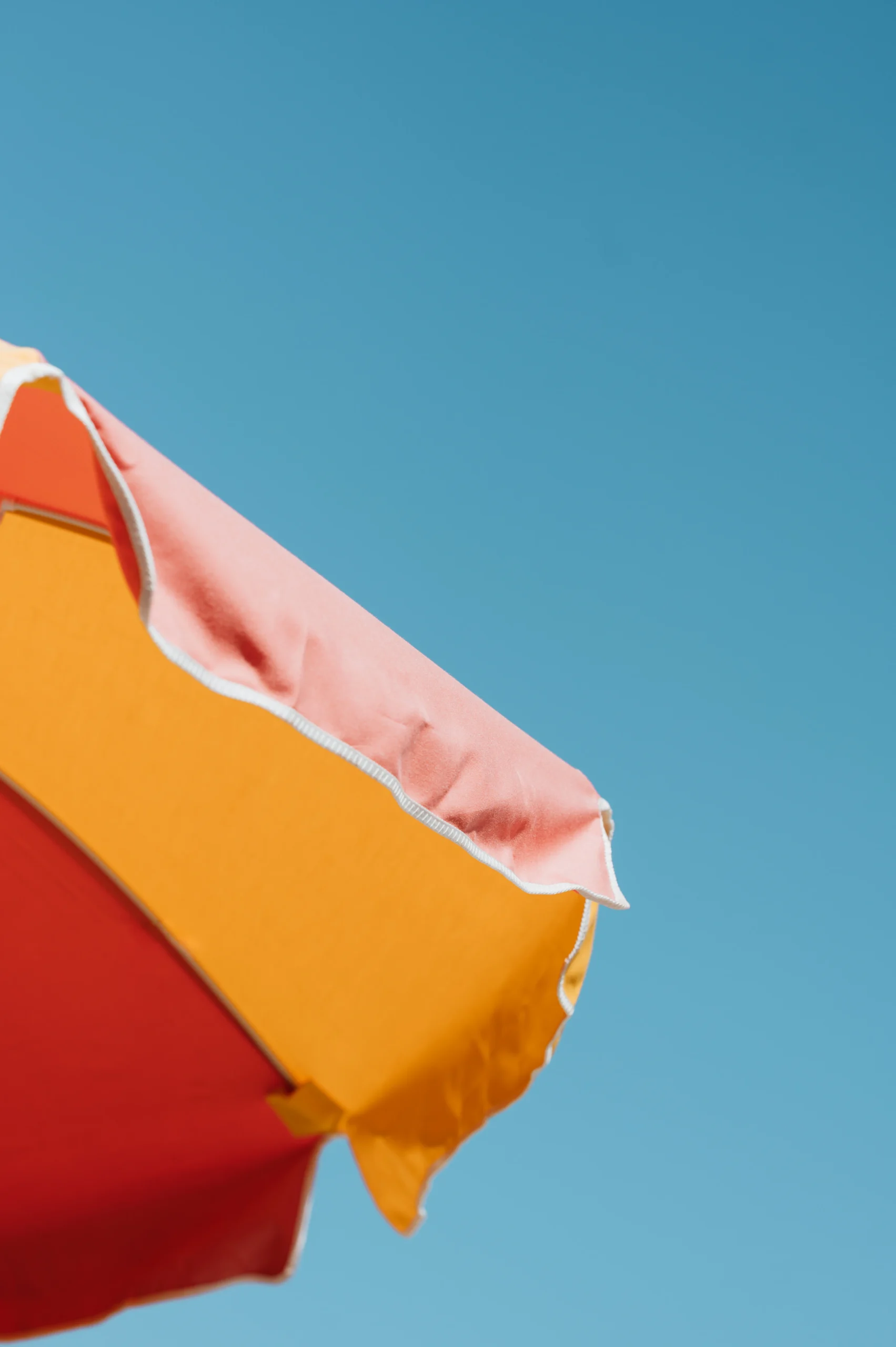 close up photo of beach umbrella with blue sky in the background