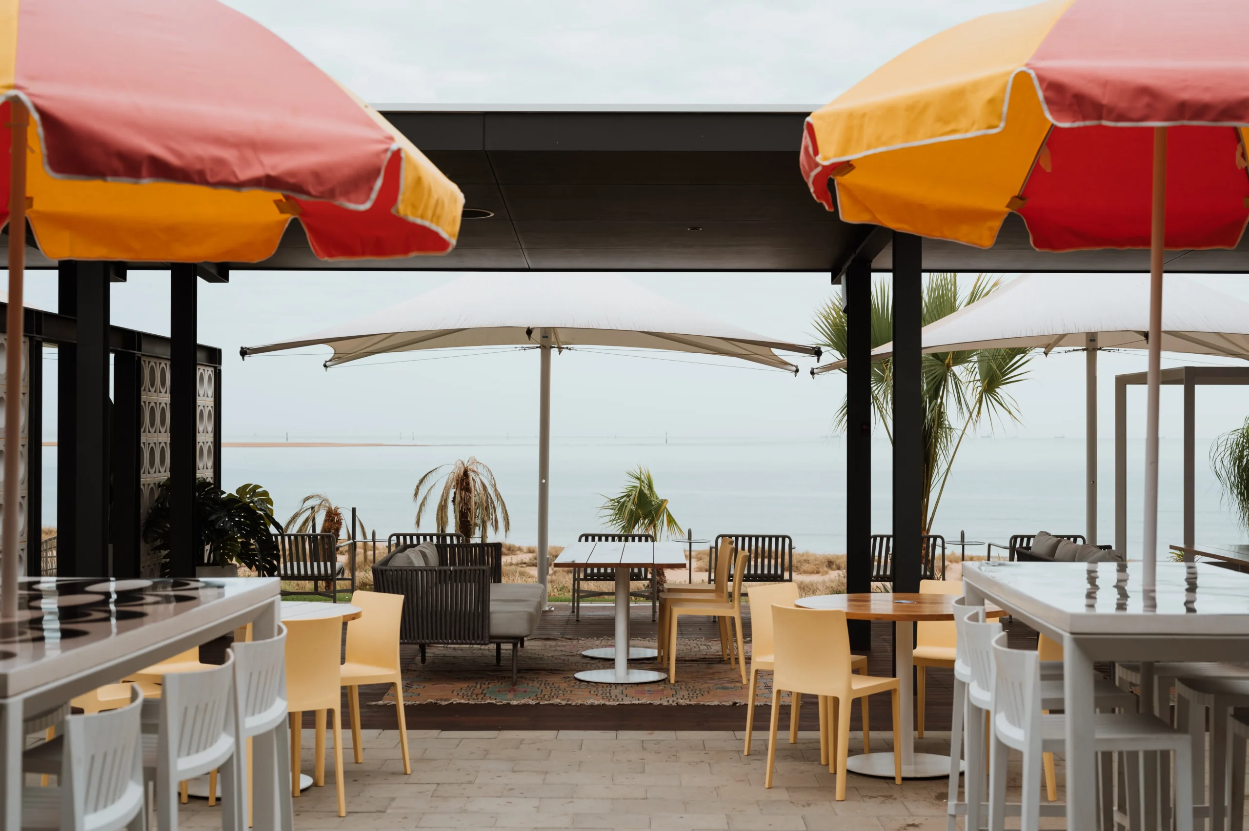 Photo of the exterior dining area at Rays Port Hedland with beach umbrellas and the ocean in the background