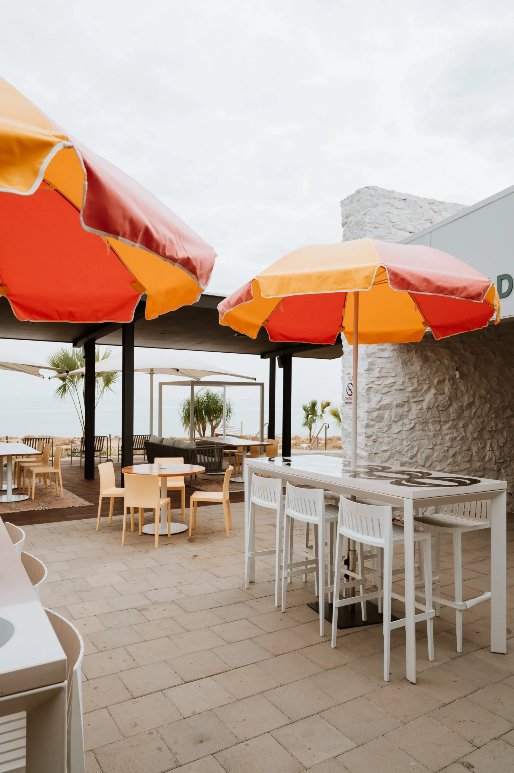 Photo of the exterior dining area at Rays Port Hedland with beach umbrellas and the ocean in the background