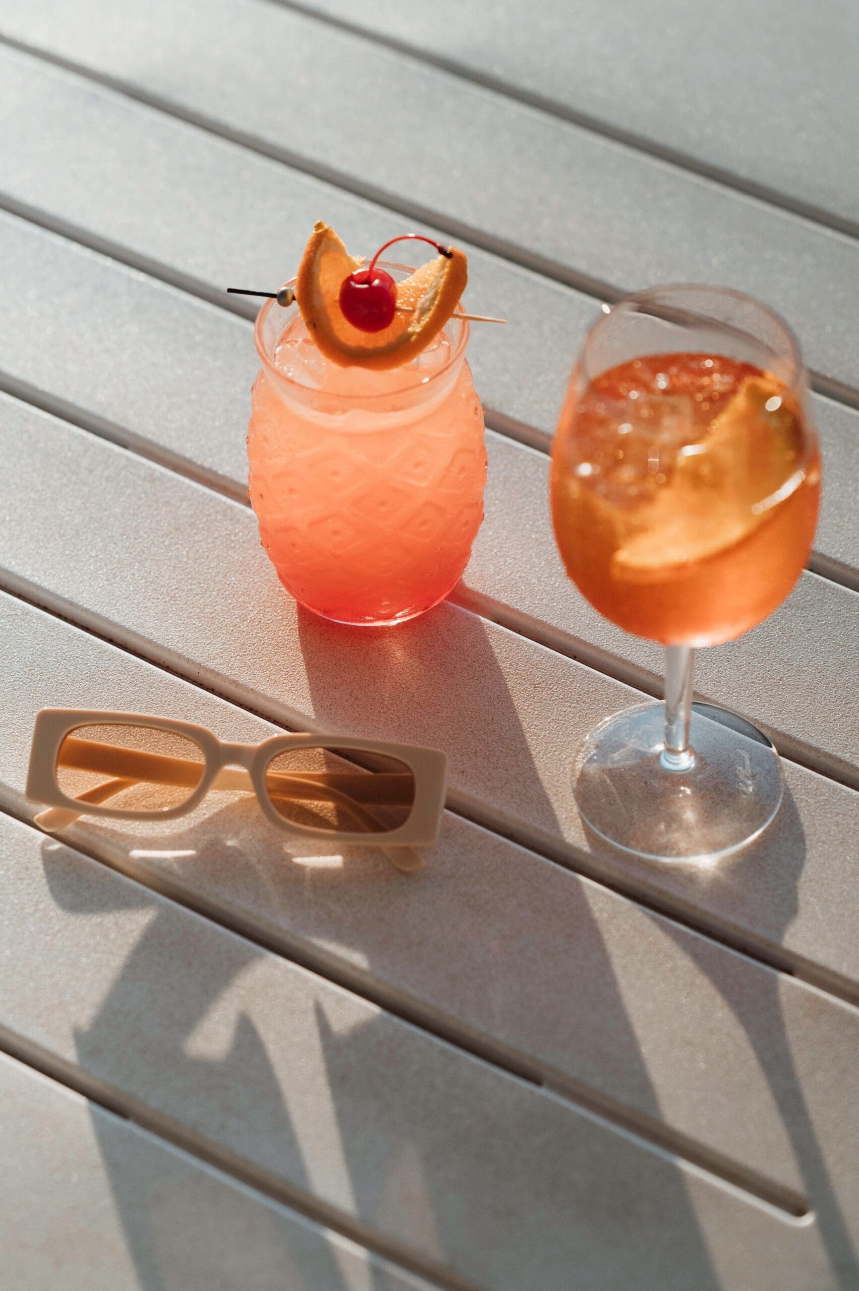 A cocktail, an aperol spritz and a pair of sunglasses sitting on a table at the Hedland Hotel