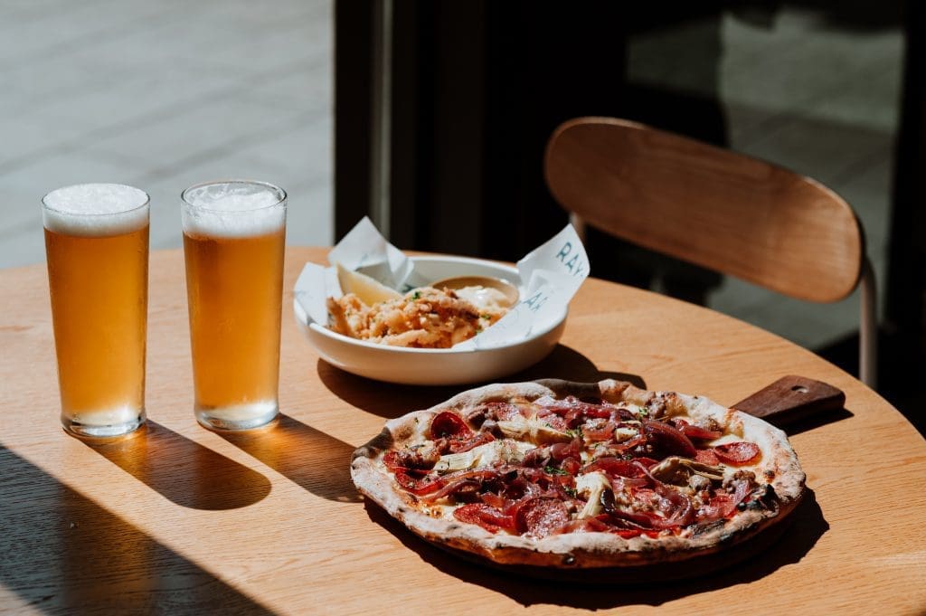 Image of pizza and beers from Rays, the photo is taken in the evening with sunset causing a shadow